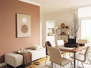 Neutral dining space with timber table and cream chairs and brown blanket on cushion bench plant